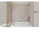 A tiled shower and tub combination in a bathroom with neutral tile at 11317 Wickersley Pl, Tampa, FL 33625