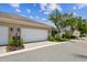 View of the home's exterior featuring a white two-car garage and meticulously maintained lawn at 11317 Wickersley Pl, Tampa, FL 33625