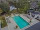 Aerial view of a rectangular pool with lounge chairs and a covered seating area, surrounded by lush landscaping and a lake at 11317 Wickersley Pl, Tampa, FL 33625