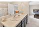 Bright bathroom with double sinks, a large mirror, and a doorway leading to the Primary bedroom at 12710 Buffalo Run Drive, Gibsonton, FL 33534