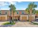 Inviting townhome featuring a two-car garage, lovely landscaping, and mature palm trees at 12710 Buffalo Run Drive, Gibsonton, FL 33534