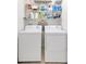 Bright laundry room with washer, dryer, and shelves stocked with laundry supplies at 12710 Buffalo Run Drive, Gibsonton, FL 33534