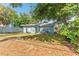 The backyard features a large lawn, mature trees, and a charming light blue home exterior at 1327 S Michigan Ave, Clearwater, FL 33756