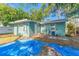 View of backyard with green siding, a blue tarp, and verdant trees enhancing the property at 1327 S Michigan Ave, Clearwater, FL 33756