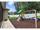 Backyard featuring a playset, white fence, paver border, and meticulous landscaping at 13310 Tiger Lilly Ln, Tampa, FL 33625