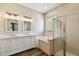 Elegant bathroom featuring dual sinks, a soaking tub, a glass-enclosed shower and wood-look floors at 13310 Tiger Lilly Ln, Tampa, FL 33625