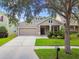 Inviting exterior showcasing a two-car garage, manicured lawn, and beautiful landscaping at 13310 Tiger Lilly Ln, Tampa, FL 33625