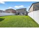 Wide view of a spacious backyard, enclosed by a white fence, and featuring green grass at 13324 Willow Bluestar Loop, Riverview, FL 33579
