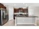 Kitchen island features a stainless steel refrigerator and granite countertops, along with a double sink and faucet at 13324 Willow Bluestar Loop, Riverview, FL 33579