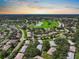 An aerial view showcasing a neighborhood with mature trees, ponds, and winding roads at sunset at 1617 Leland Dr, Sun City Center, FL 33573