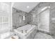 Elegant bathroom featuring soaking tub, glass shower, and marble walls at 1628 Long Bow Ln, Clearwater, FL 33764