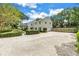 Gravel and brick-paved driveway leading to a two-story home with a lush, green yard at 1628 Long Bow Ln, Clearwater, FL 33764