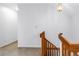 Hallway with stairs featuring wood railing, white walls, and neutral carpeting at 1628 Long Bow Ln, Clearwater, FL 33764
