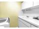 Laundry room with a utility sink, tiled backsplash, and a modern washing machine at 1628 Long Bow Ln, Clearwater, FL 33764