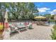 Relaxing patio area with comfortable seating and shade umbrellas adjacent to a tennis court at 1628 Long Bow Ln, Clearwater, FL 33764