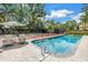 Relaxing poolside with lounge chairs, view of tennis court, and lush green landscaping at 1628 Long Bow Ln, Clearwater, FL 33764