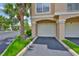 Attached garage with a paved driveway, lush green grass, and landscaping on both sides at 2201 Bay Club Cir, Tampa, FL 33607