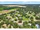 Expansive aerial view of a neighborhood surrounded by green fields, mature trees, and a tranquil lake at 2515 Pemberton Creek Dr, Seffner, FL 33584