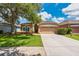 Charming single-story home with well-maintained lawn, mature tree, and attached two-car garage at 27652 Sky Lake Cir, Wesley Chapel, FL 33544