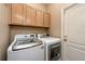 Laundry room with side-by-side washer and dryer and oak cabinets at 27652 Sky Lake Cir, Wesley Chapel, FL 33544