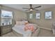 Inviting bedroom with three windows, ceiling fan, and plush bed adorned with decorative pillows at 2866 Quail Crest Ct, Valrico, FL 33594