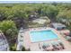 Aerial view of community pool with lounge chairs, umbrellas, and tennis courts in the background at 3335 Fox Hunt Dr, Palm Harbor, FL 34683