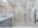 Modern bathroom with grey vanity cabinets and walk-in shower with a rainfall showerhead and elegant tile at 33369 Hamilton Hill Ln, Wesley Chapel, FL 33545