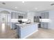 Open-concept kitchen with grey cabinets, stainless steel appliances, a quartz island, and tile flooring at 33369 Hamilton Hill Ln, Wesley Chapel, FL 33545