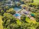 Aerial view of community pool, tennis courts, playground, and picnic area nestled within lush greenery at 34811 Arbor Green Pl, Zephyrhills, FL 33541