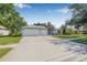 Inviting home exterior featuring a three-car garage, well-maintained lawn, and mature trees at 34811 Arbor Green Pl, Zephyrhills, FL 33541