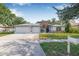 Charming single-story home featuring a well-manicured lawn, flowerbeds, and a spacious three-car garage at 34811 Arbor Green Pl, Zephyrhills, FL 33541