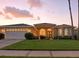 Charming single-story home with a well-manicured lawn, beautiful landscaping, and arched windows at sunset at 4428 Gevalia Dr, Brooksville, FL 34604