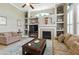 Cozy living room showcasing a fireplace, built-in shelves, and plush seating, with natural light filtering through large windows at 4428 Gevalia Dr, Brooksville, FL 34604