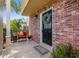 Charming brick home featuring a black front door with wreath and a cozy porch with seating at 4915 Stolls Ave, Tampa, FL 33615