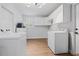 Bright laundry room with white cabinets, a utility sink and modern front load washer and dryer units at 4915 Stolls Ave, Tampa, FL 33615