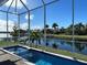 View of a long swimming pool surrounded by a screen enclosure and a canal view at 5307 Wishing Arch Dr, Apollo Beach, FL 33572