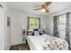 Bedroom with a wooden ceiling fan, laminate floors, two windows, and a floral comforter at 5741 91St N Ave, Pinellas Park, FL 33782