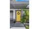 Close-up of a bright yellow front door with a wreath and nearby greenery, sheltered by a carport at 5741 91St N Ave, Pinellas Park, FL 33782