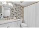 Stylish bathroom features a patterned accent wall, round mirror, and white vanity with marble countertop at 602 Lime Ave # 102, Clearwater, FL 33756