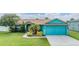 Charming single-story home boasts vibrant curb appeal with blue paint, lush landscaping, and an attached two-car garage at 7046 Frascati Loop, Wesley Chapel, FL 33544