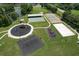 Overhead view of a community park with a playground, tennis courts and a volleyball court on a bright, sunny day at 7254 Parkersburg Dr, Wesley Chapel, FL 33545