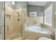 Bright bathroom featuring a walk-in shower and separate soaking tub with neutral tiling at 7254 Parkersburg Dr, Wesley Chapel, FL 33545