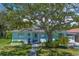 Charming single-story light blue home with a lush green lawn, mature tree, and decorative beach access point at 745 Bruce Ave, Clearwater Beach, FL 33767