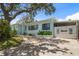 Charming light blue single-story home with lush landscaping, a welcoming walkway, and a decorative beach access point at 745 Bruce Ave, Clearwater Beach, FL 33767