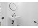 Modern powder room with a pedestal sink, round mirror, and sleek black hardware at 7617 Alvina St, Tampa, FL 33625
