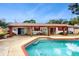 Spacious backyard with an in-ground pool, patio area, and mature trees providing shade at 7710 Jackson Springs Rd, Tampa, FL 33615