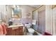A bathroom with a single sink, a mirror, a toilet, and a shower with pink tiling and floral wallpaper at 7710 Jackson Springs Rd, Tampa, FL 33615