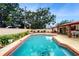 Beautiful pool featuring a brick-trimmed edge, surrounded by lush landscaping at 7710 Jackson Springs Rd, Tampa, FL 33615