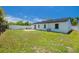 Spacious backyard with a lush lawn, white fence, mature trees, and patio furniture at 7815 Shadow Run Dr, Largo, FL 33773