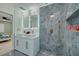 Modern bathroom boasts dual sinks, stylish mirrors, and a luxurious blue-tiled shower with gold fixtures at 7815 Shadow Run Dr, Largo, FL 33773